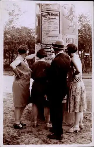 Foto Ak Mann und Frauen vor einer Litfaßsäule