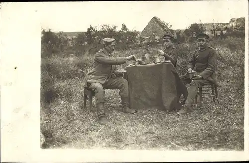 Foto Ak Deutsche Soldaten in Uniformen an einem Tisch auf einer Wiese, I WK
