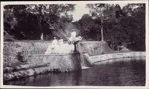 Foto Ak Namada Insel Bali Indonesien, Personen auf einer Mauer am Wasser