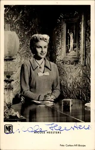 Ak Schauspielerin Nicole Heesters, Portrait, Autogramm,  an einem Tisch sitzend