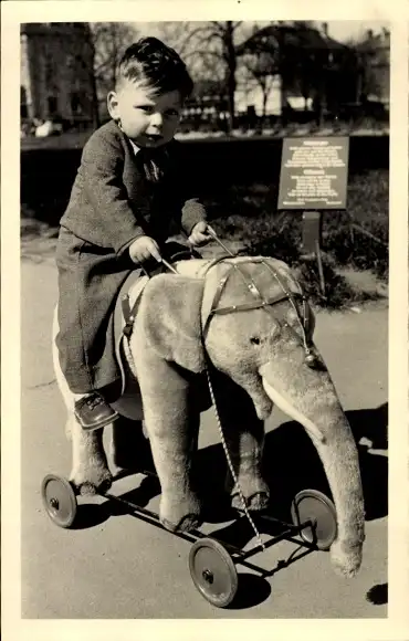 Foto Ak Junge auf einem Plüschelefant auf Rollen, Portrait