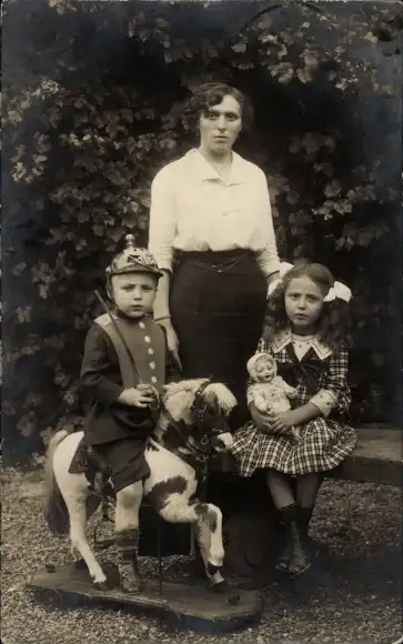 Foto Ak Junge in Uniform auf einem Schaukelpferd, Mädchen mit Puppe, Portrait