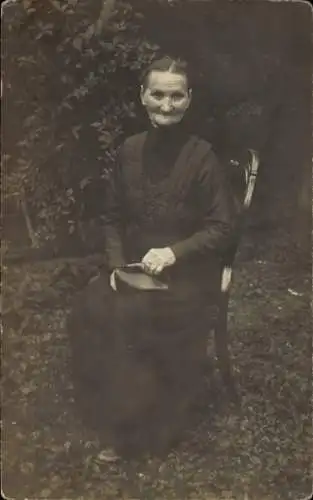 Foto Ak Portrait einer älteren Frau auf einem Stuhl im Garten