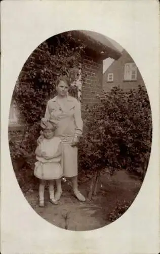 Foto Ak Frau mit Mädchen in einem Garten vor einem Haus, Portrait