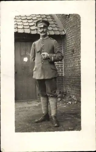 Foto Ak Deutscher Soldat in Uniform, Standportrait, Schirmmütze, Achselschnur, Zigarre, I. WK
