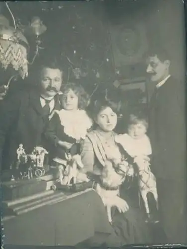 Foto Familienportrait vor dem Weihnachtsbaum, Kinder mit Spielzeugen