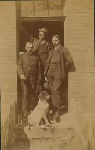 Foto Drei Männer mit Hund in einem Hauseingang