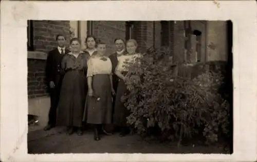 Foto Ak Männer und Frauen vor einem Backsteinhaus