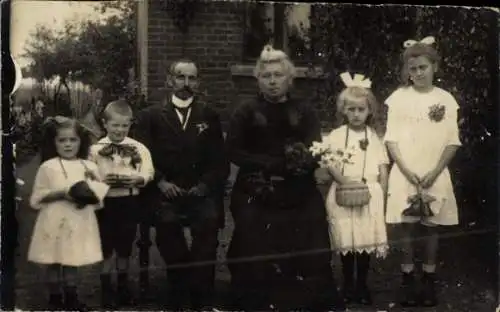 Foto Älteres Paar und vier Kinder vor einem Haus