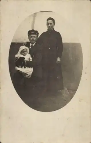 Foto Ak Familienportrait, Mann mit Baby auf dem Schoß, stehende Frau