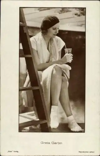 Ak Schauspielerin Greta Garbo, Sitzportrait, Mütze, Glas