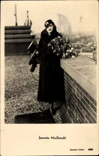 Ak Schauspielerin Jeanette MacDonald, Portrait auf dem Dach mit Blumenstrauss