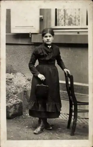 Foto Ak Junge Frau in schwarzem Kleid, Portrait, Handtasche, Stuhl