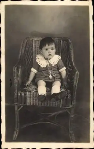 Foto Ak Kleinkind mit Nuckel auf einem Korbstuhl, Portrait