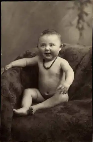 Foto Ak Kinderportrait, Baby mit Perlenkette auf einem Sessel