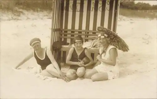 Foto Ak Drei Frauen am Strand, Badeanzug, Strandkorb, Sonnenschirm