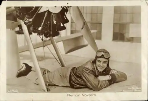 Ak Schauspieler Ramon Novarro, Portrait, Fliegermontur, liegend, Flugzeugmotor