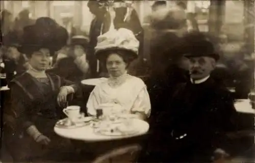 Foto Ak Zwei Frauen und Mann am Tisch, Tassen, Kaffee, Tee