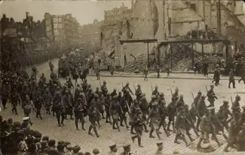 Foto Ak Deutsche Soldaten in Uniformen auf dem Marsch durch zerstörte Ortschaft, I WK