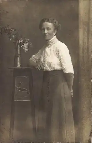 Foto Ak Junge Frau in schwarzem Rock, Standporträt, Blumenvase, Weiße Bluse