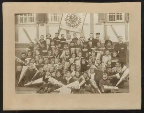 Fotografie Gruppenbild Kinder mit ihrer Zuckertüte vor Schulgebäude, Lehrer, Fahne, 1914