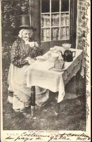 Ak Wales, Frau in Volkstracht, Tisch, Teekanne, Tasse