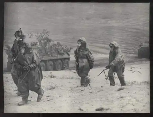 Fotografie DDR NVA-Soldaten in Schutzausrüstung während eines Manövers, Panzer im Hintergrund