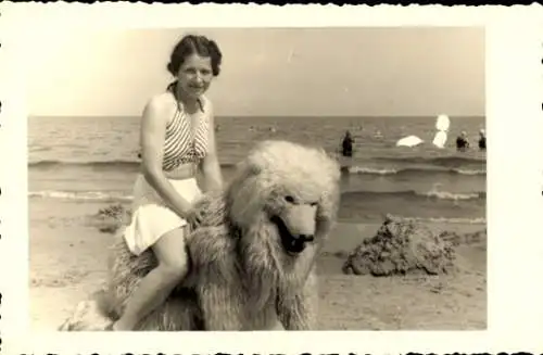 Foto Ak Junge Frau in Bademode am Strand, auf einer Person im Eisbärenkostüm sitzend