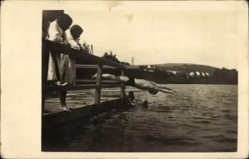 Foto Ak Řevnice Rewnitz Mittelböhmen, Badestelle, junger Mann springt vom Steg ins Wasser