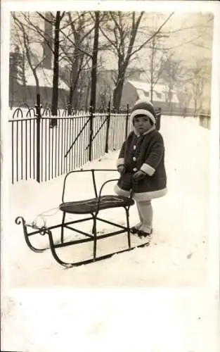 Foto Ak Mädchen in Wintermantel, Schlitten, Schnee