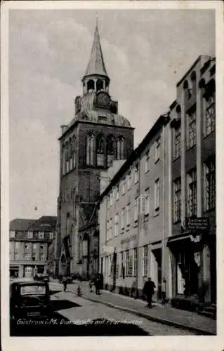 Ak Güstrow Mecklenburg, Domstraße mit der Pfarrkirche, Sattlerei Paul Krüger