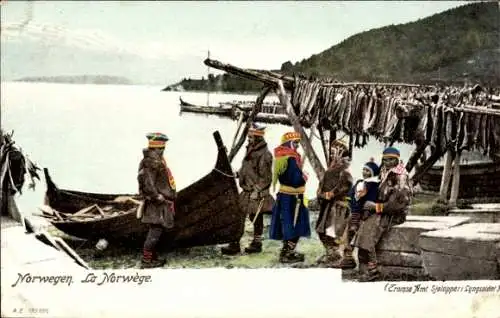 Ak Norwegen, Norweger in Winterkleidung am Ufer, Trocknende Fische