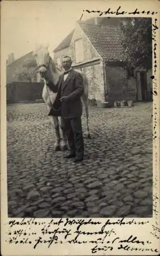 Foto Ak Preetz in Holstein, Mann in Anzug, Standportrait mit einem Pferd