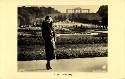 Ak Schauspielerin Lilian Harvey, Standportrait, Gartenanlagen