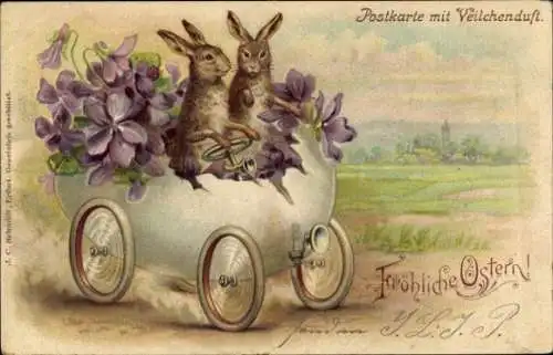 Litho Frohe Ostern, Zwei Hasen in einem aus einem Ei gebauten Auto mit Veilchen.