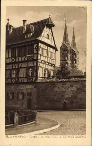 Ak Bamberg in Oberfranken, Fachwerkhaus, dahinter zwei Kirchtürme, davor eine Stadtmauer mit Z...