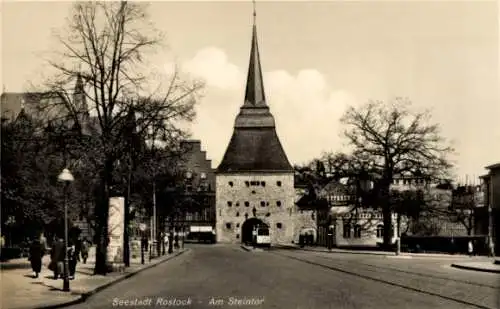 Ak Hansestadt Rostock, Seestadt  Am Steintor, historisches Tor, Straßenansicht, Bäume, Fußgänger