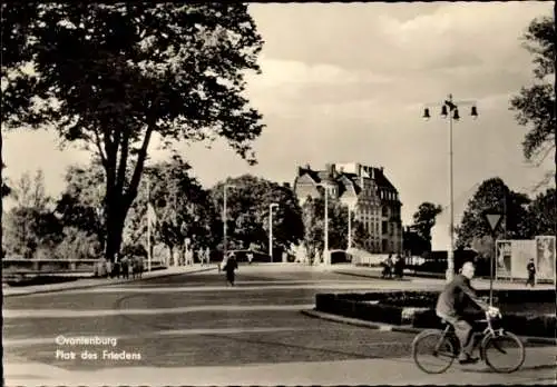 Ak Oranienburg in Brandenburg, Straßenszene mit Bäumen und Gebäuden, ein Mann mit Fahrrad ist ...