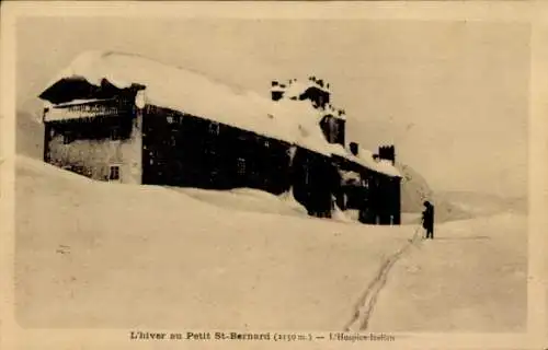 Ak Le Petit St. Bernard Savoie,  verschneite Landschaft, Gebäude, eine Person mit Skiern