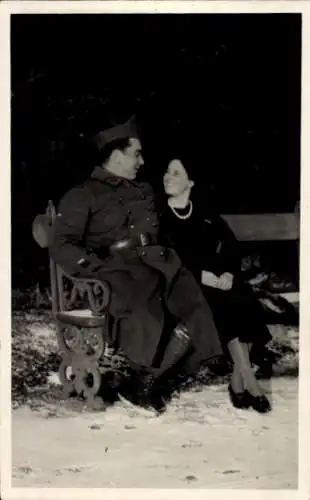 Foto Ak Französischer Soldat in Uniform, Porträt mir Frau, Sitzbank, Winter, Schnee