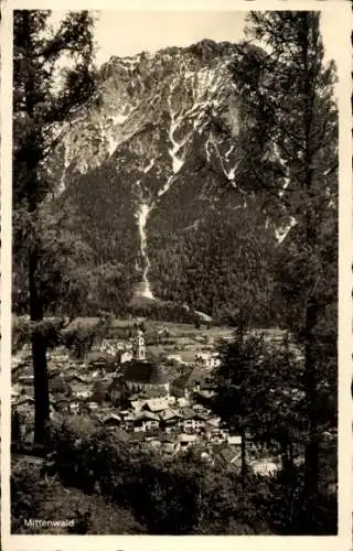 Ak Mittenwald in Oberbayern,  verschneite Berglandschaft mit Nadelbäumen im Vordergrund, dahin...