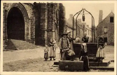 Ak Locronan Finistère, Straßenszene mit Brunnen, davor steht ein Mann mit zwei Kindern, weiter...