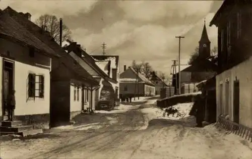 Ak Kutná Hora Kuttenberg Mittelböhmen, Schneebedeckte Straße, alte Häuser, Kirchturm im Hinter...