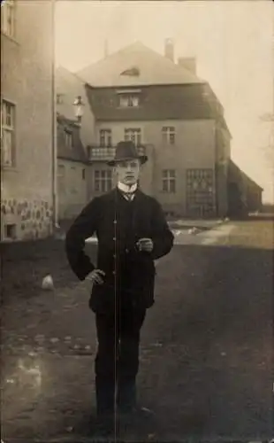 Foto Ak Junger Mann mit Hut steht vor einem Haus