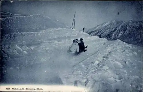 Ak Kilchberg Kanton Zürich, Zwei Personen auf einem Schlitten, die einen Berg hinunterfahren. ...