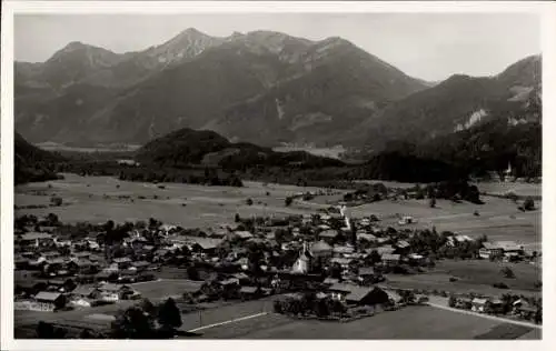 Ak Unterwössen in Oberbayern, Luftaufnahme,  Gebäude, Wiesen, Berge im Hintergrund, Geigelstein