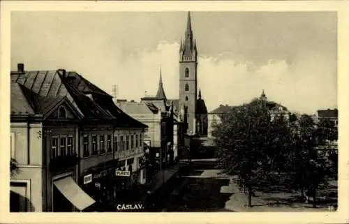 Ak Čáslav Tschaslau Mittelböhmen, Stadtansicht mit Kirche, Gebäude im Vordergrund, Schild 'Pla...