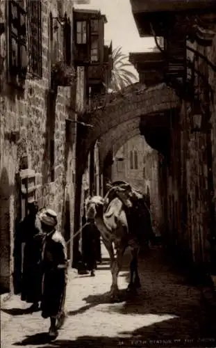 Ak Jerusalem Israel, Förfte Station des Kreuzwegs. Ein Mann führt ein Kamel durch einen engen ...