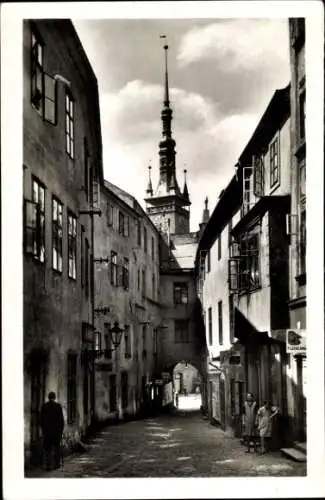 Ak Olomouc Olmütz Stadt, Schmaler Weg, hohe Gebäude, Kirchturm im Hintergrund