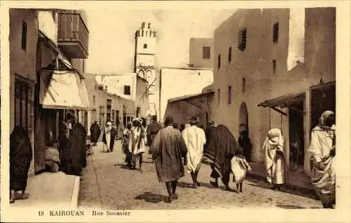 Ak Kairouan Tunesien, Stadtansicht, Straße, Menschen in traditioneller Kleidung, Turm im Hinte...